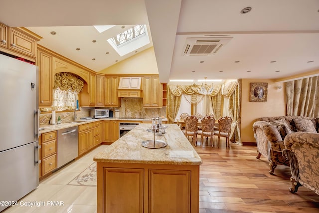 kitchen featuring open floor plan, stainless steel appliances, a kitchen island, and light stone countertops