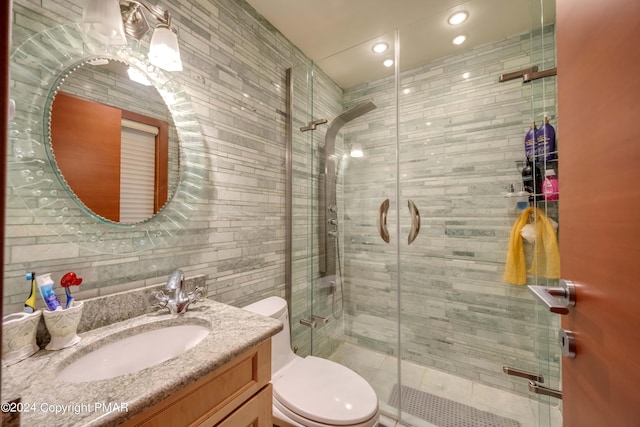 bathroom featuring toilet, a shower stall, and vanity