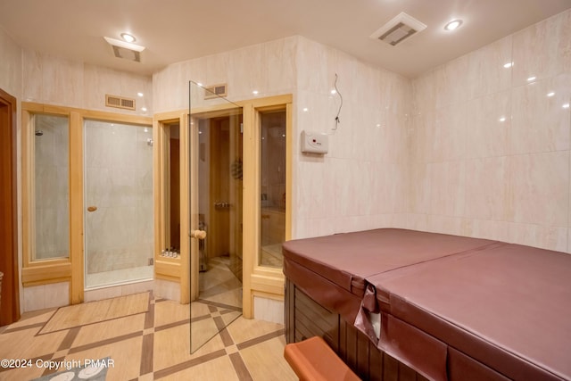 bathroom featuring a stall shower, recessed lighting, visible vents, and tile walls