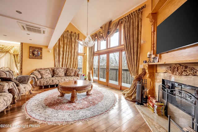 living room featuring hardwood / wood-style flooring, a fireplace, visible vents, and high vaulted ceiling