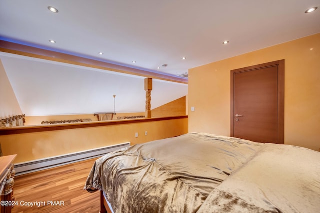 bedroom with a baseboard heating unit, wood finished floors, and recessed lighting