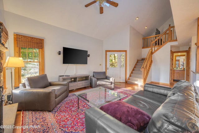 living area with recessed lighting, high vaulted ceiling, stairs, a ceiling fan, and wood finished floors