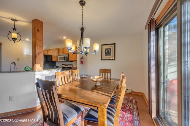 dining area with a wealth of natural light, light wood finished floors, a notable chandelier, and baseboards