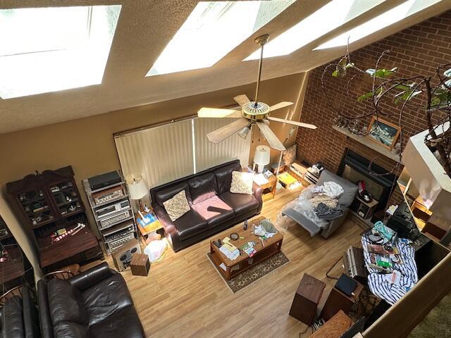326 Somerset Dr, East Stroudsburg, PA 18301 - living room with a skylight, brick wall, wood finished floors, a ceiling fan, and vaulted ceiling