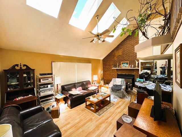 326 Somerset Dr, East Stroudsburg, PA 18301 - living area with a skylight, wood finished floors, high vaulted ceiling, a brick fireplace, and ceiling fan