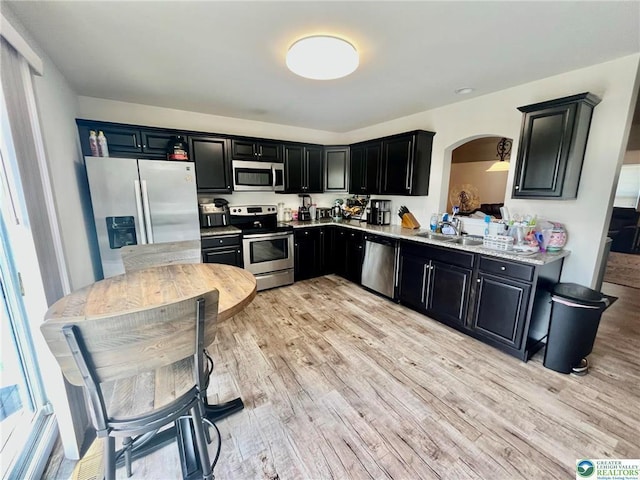 630 Lehigh Gap St, Walnutport, PA 18088 - kitchen with appliances with stainless steel finishes, dark cabinetry, arched walkways, and light wood finished floors