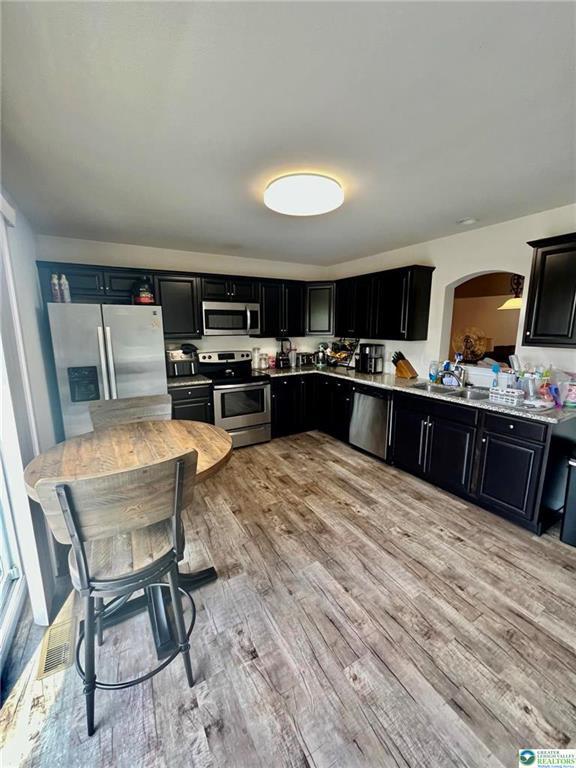 630 Lehigh Gap St, Walnutport, PA 18088 - kitchen featuring appliances with stainless steel finishes, dark cabinetry, light wood finished floors, arched walkways, and light countertops