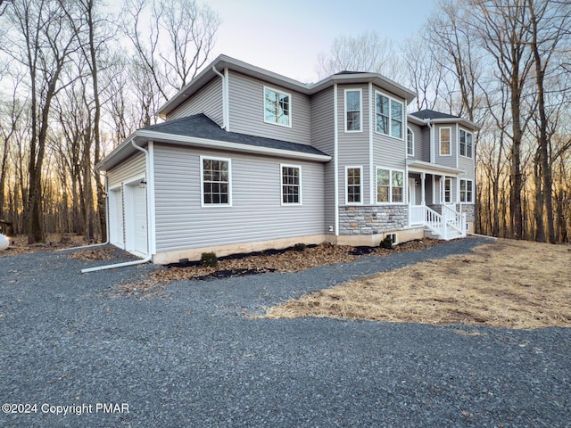 view of front of home featuring a garage, covered porch, and a shingled roof