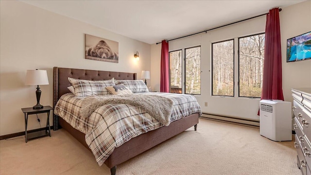 bedroom featuring a baseboard heating unit, light carpet, and baseboards