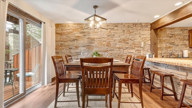 dining space with beamed ceiling, a notable chandelier, and light wood-type flooring