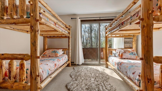 bedroom featuring access to exterior, carpet flooring, and rustic walls