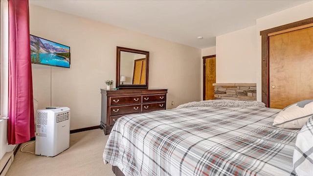 bedroom featuring a baseboard heating unit, baseboards, and light colored carpet