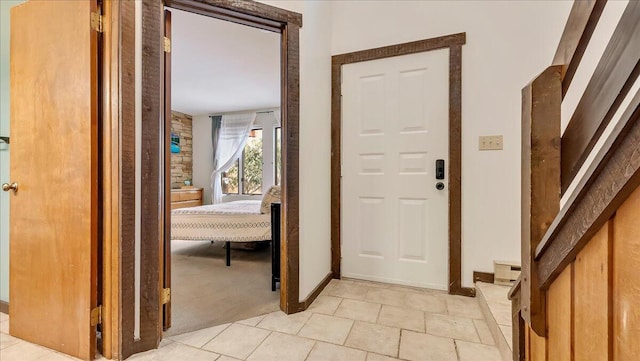 foyer featuring light colored carpet and baseboards