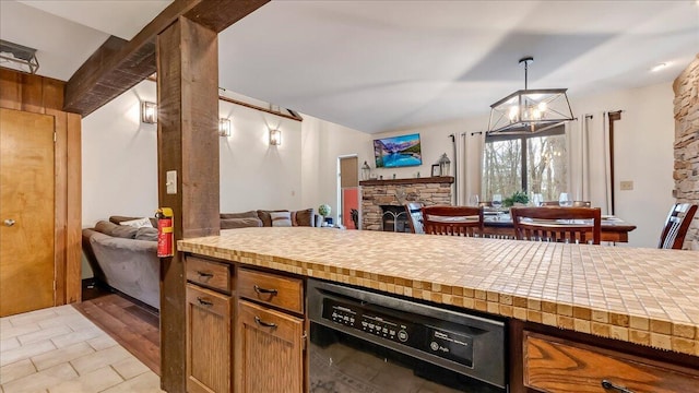 kitchen with black dishwasher, open floor plan, a fireplace, and light countertops