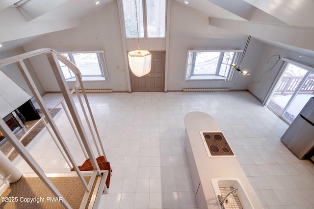 entryway featuring light tile patterned floors, a wealth of natural light, high vaulted ceiling, and baseboard heating