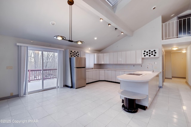 kitchen with beamed ceiling, stainless steel fridge, kitchen peninsula, pendant lighting, and white cabinets