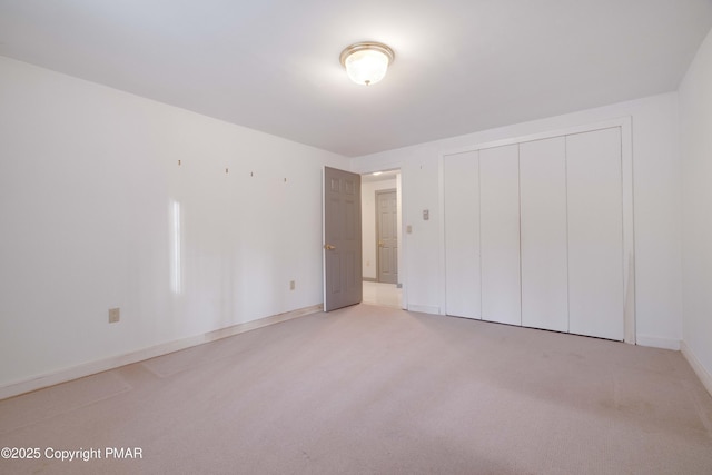 unfurnished bedroom with light carpet and a closet