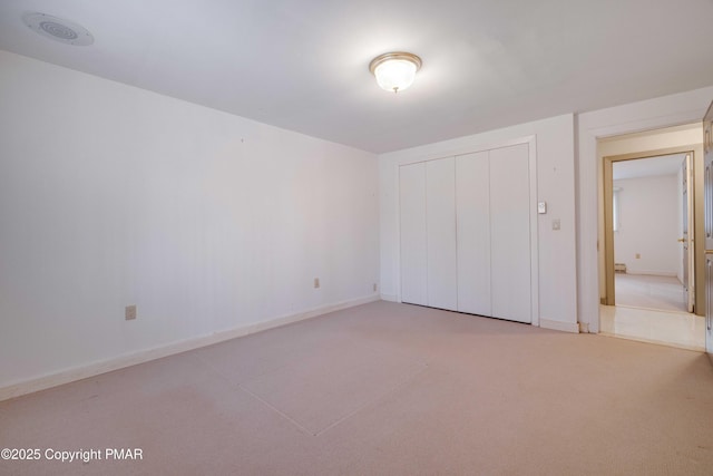 unfurnished bedroom featuring light colored carpet and a closet