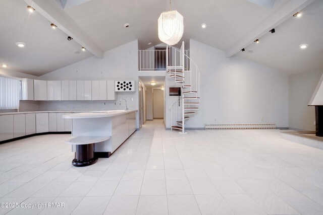 kitchen with sink, white cabinetry, hanging light fixtures, a kitchen island with sink, and beamed ceiling