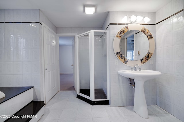 bathroom featuring tile patterned flooring, tile walls, and a shower with shower door