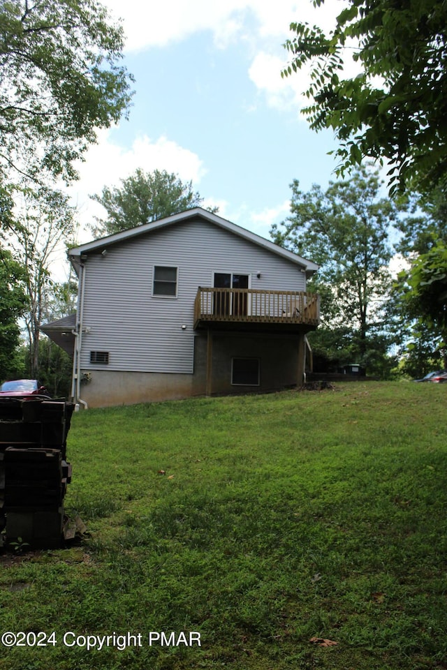 back of house featuring a lawn and a wooden deck