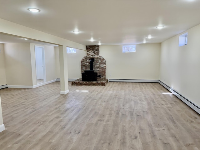 248 Seneca Dr, Milford, PA 18337 - below grade area with a wood stove, light wood-style floors, baseboard heating, and a baseboard heating unit