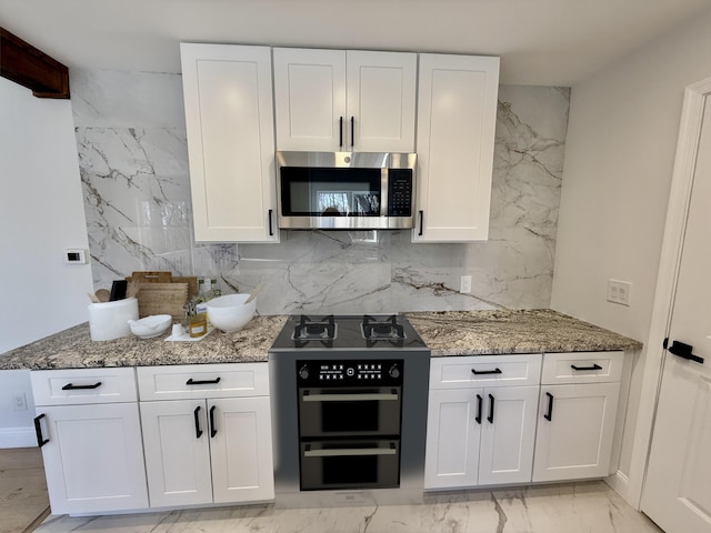 248 Seneca Dr, Milford, PA 18337 - kitchen with stainless steel microwave, light stone countertops, and white cabinetry