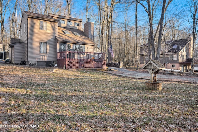 back of house with a yard, a chimney, and a wooden deck