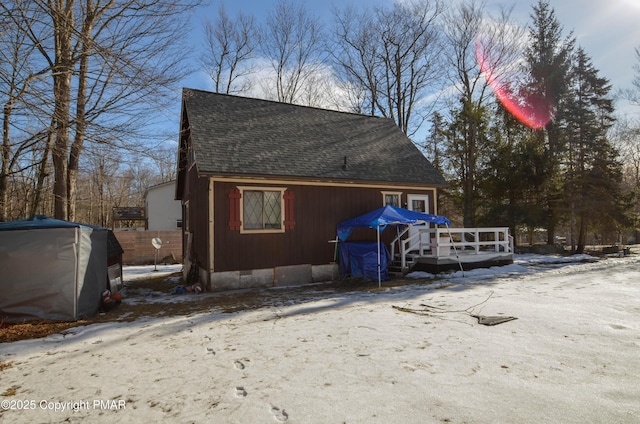 snow covered property with a deck, roof with shingles, and crawl space