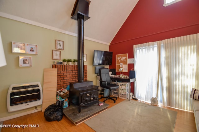 living area with lofted ceiling, wood finished floors, a wood stove, and heating unit