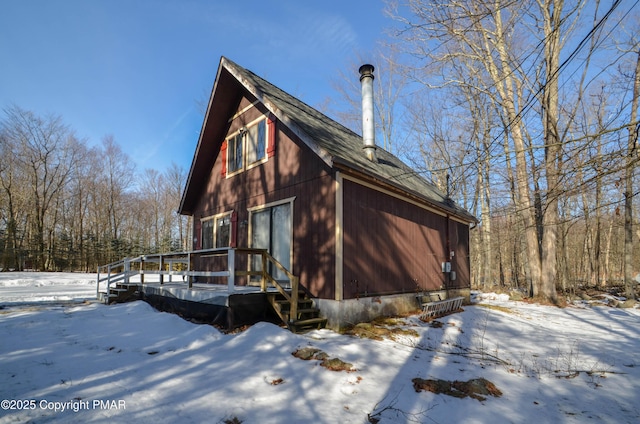 view of snow covered exterior with roof with shingles