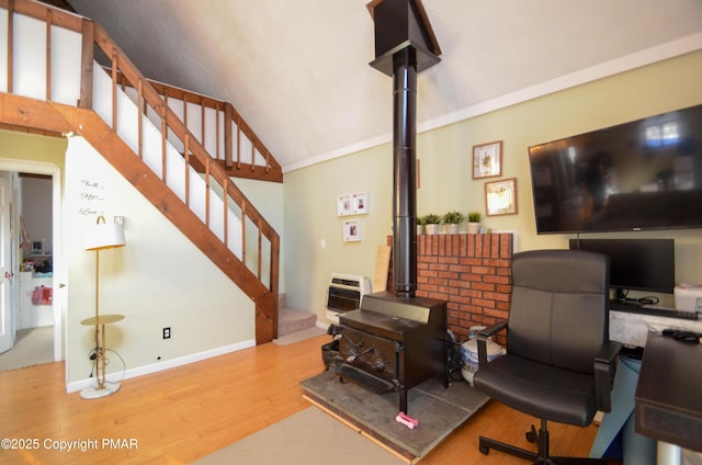 office featuring lofted ceiling, a wood stove, and light wood-type flooring