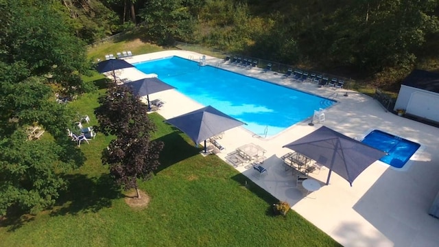 community pool with a patio, a lawn, and fence