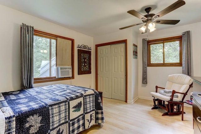 bedroom with a closet, multiple windows, baseboards, and light wood-style floors