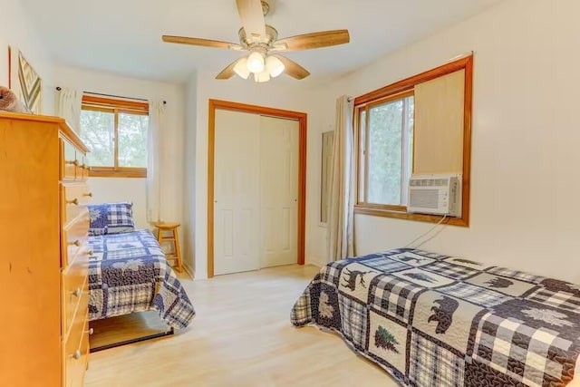 bedroom with a closet, cooling unit, a ceiling fan, and wood finished floors