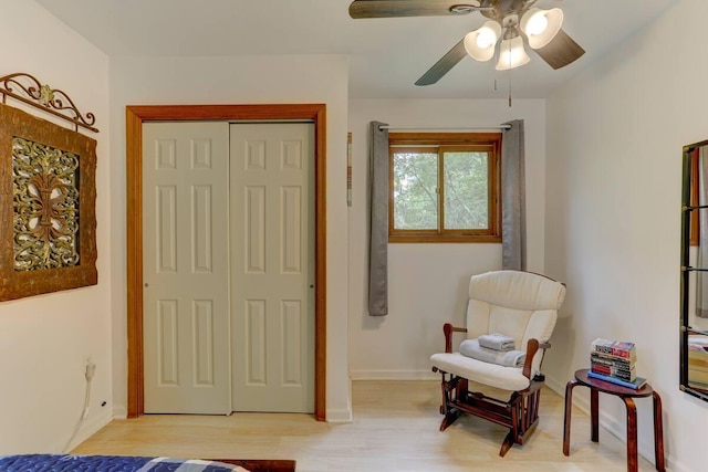 sitting room featuring a ceiling fan, light wood-type flooring, and baseboards