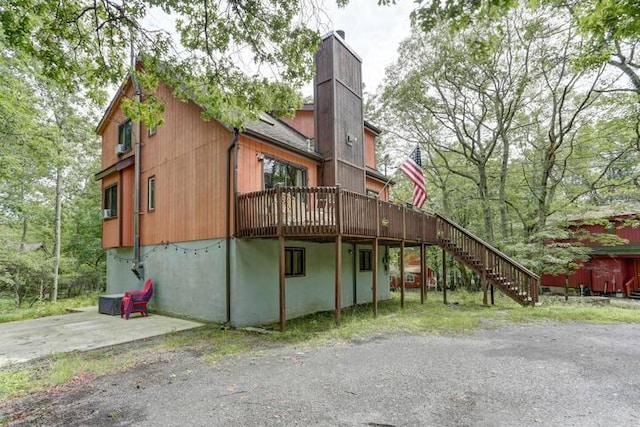 rear view of house with a wooden deck, stairway, and a chimney