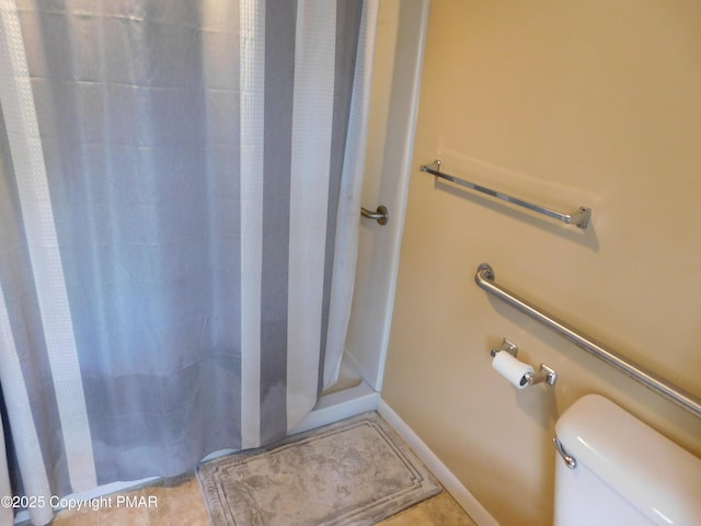 bathroom with toilet, a stall shower, tile patterned flooring, and baseboards