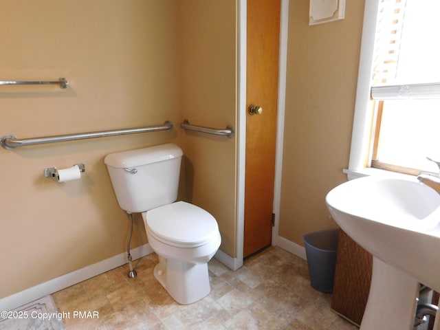 bathroom featuring a sink, toilet, and baseboards