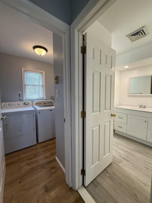 104 Sunset Dr, Mount Pocono, PA 18344 - washroom featuring washing machine and dryer, visible vents, light wood finished floors, and a sink