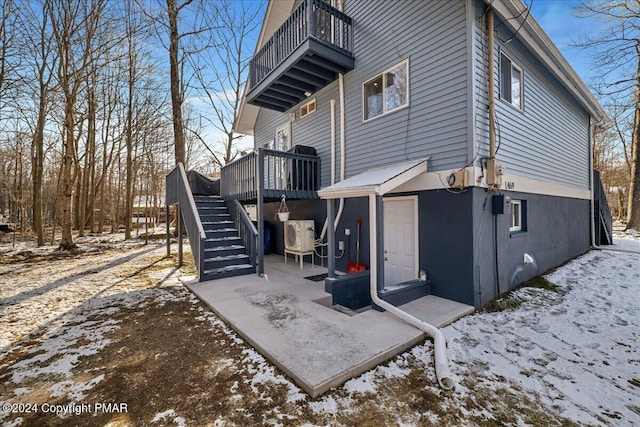 view of snowy exterior with a balcony and stairs