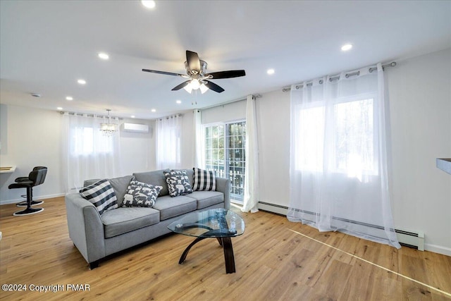 living area with a baseboard heating unit, light wood-type flooring, and a healthy amount of sunlight