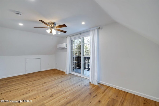 bonus room featuring lofted ceiling, light wood finished floors, baseboards, and an AC wall unit