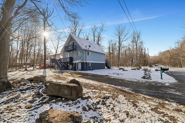 snow covered property with stairway and a wooden deck