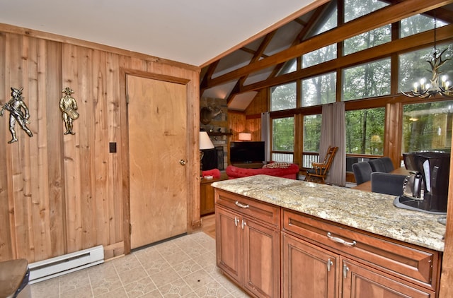 1046 Maple Dr, Pocono Lake, PA 18347 - kitchen featuring a baseboard heating unit, wood walls, light stone counters, open floor plan, and a chandelier