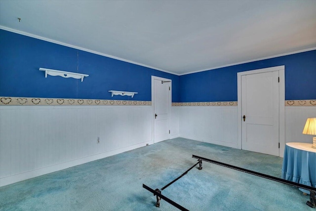 carpeted empty room featuring wainscoting and crown molding