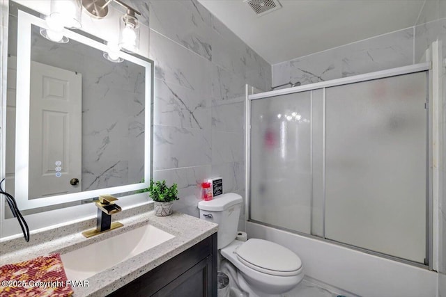 bathroom featuring marble finish floor, bath / shower combo with glass door, visible vents, toilet, and vanity