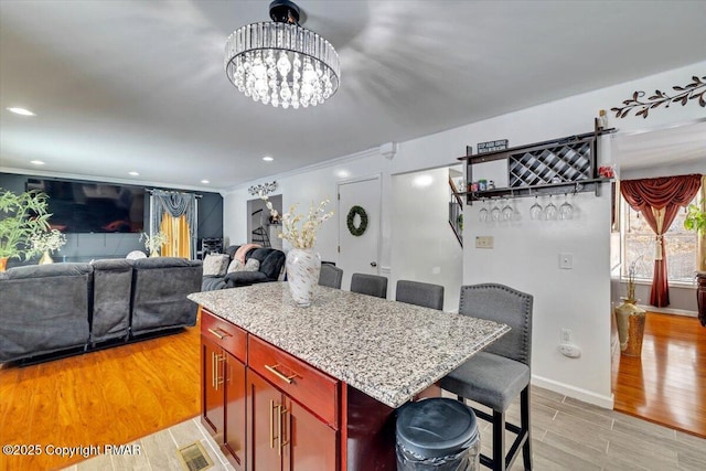 kitchen with a center island, visible vents, light wood-style floors, dark brown cabinets, and a kitchen bar