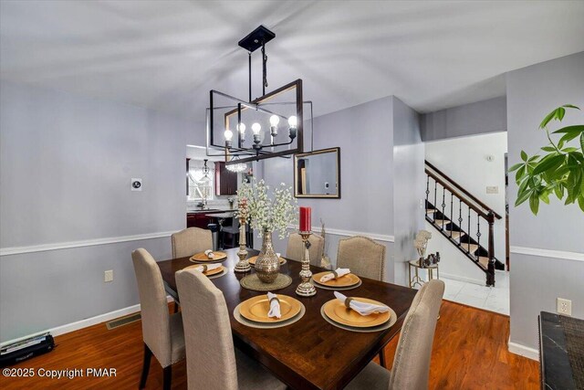 dining area with dark hardwood / wood-style floors and an inviting chandelier