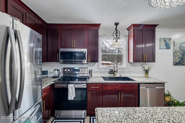 kitchen with pendant lighting, sink, appliances with stainless steel finishes, backsplash, and light stone countertops